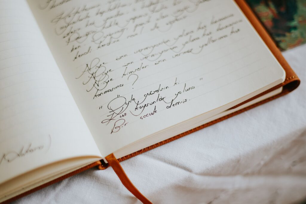 High-angle view of an open notebook with handwritten text on a white tablecloth, suggesting warmth and creativity.